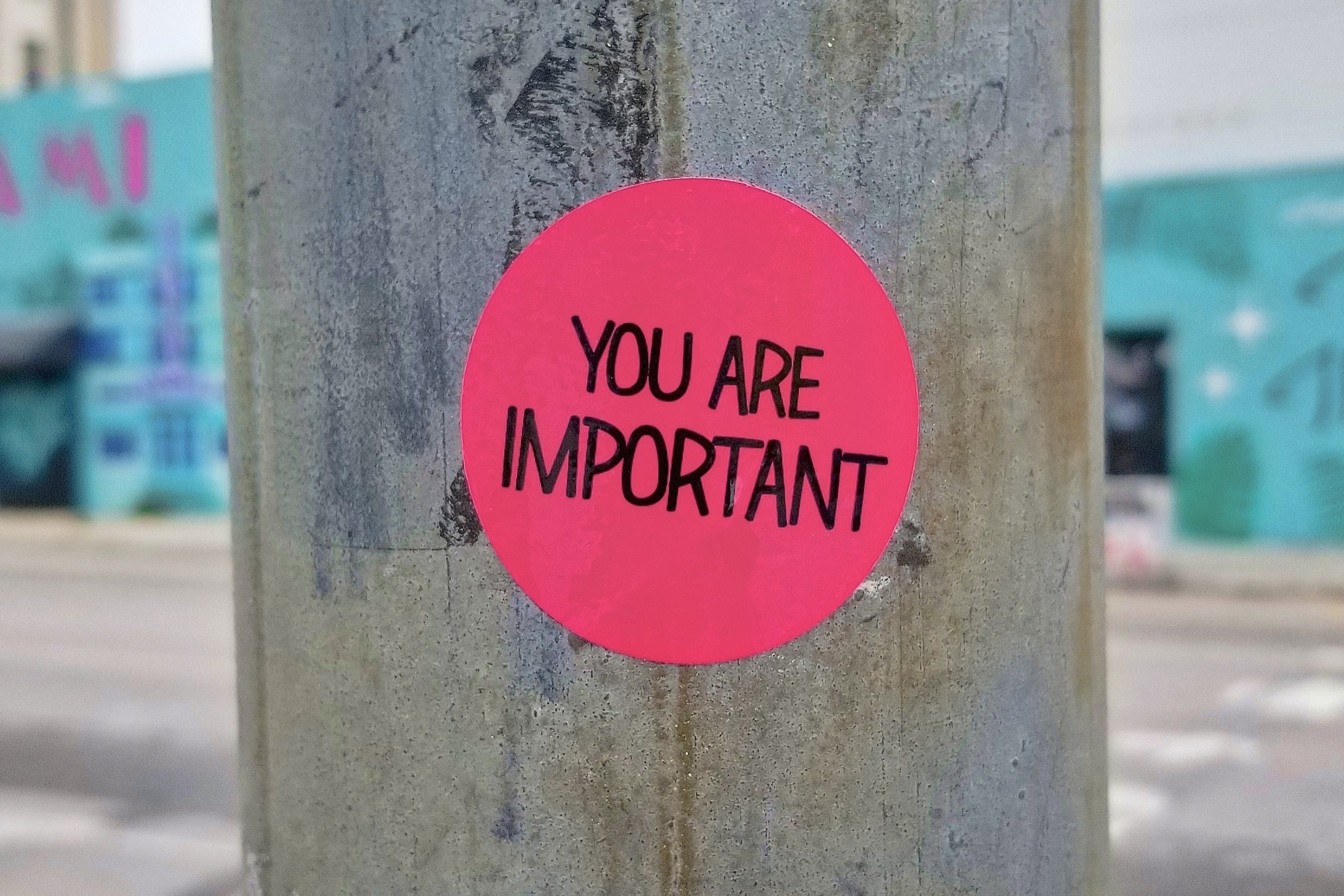 Red sticker reading 'You are important' on a lamp post in the street